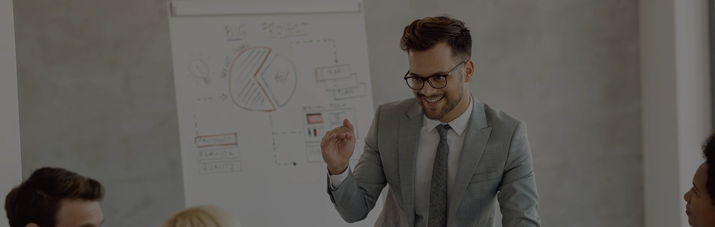 Man in a gray suit presents to colleagues