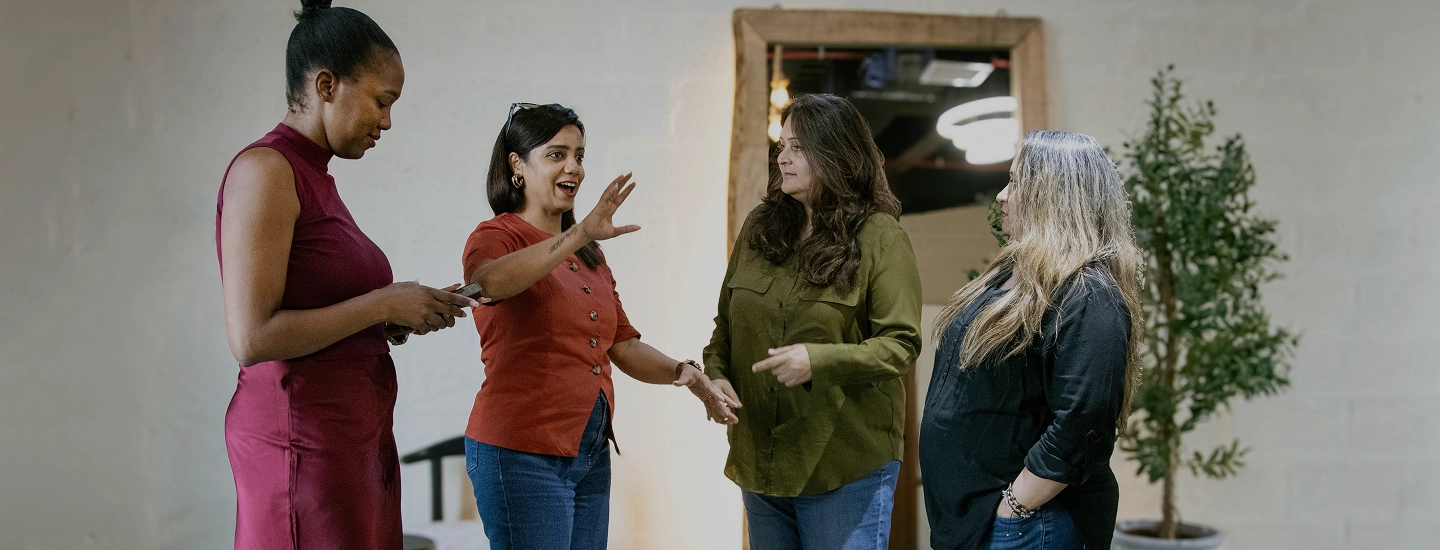 Four women standing together and conversing