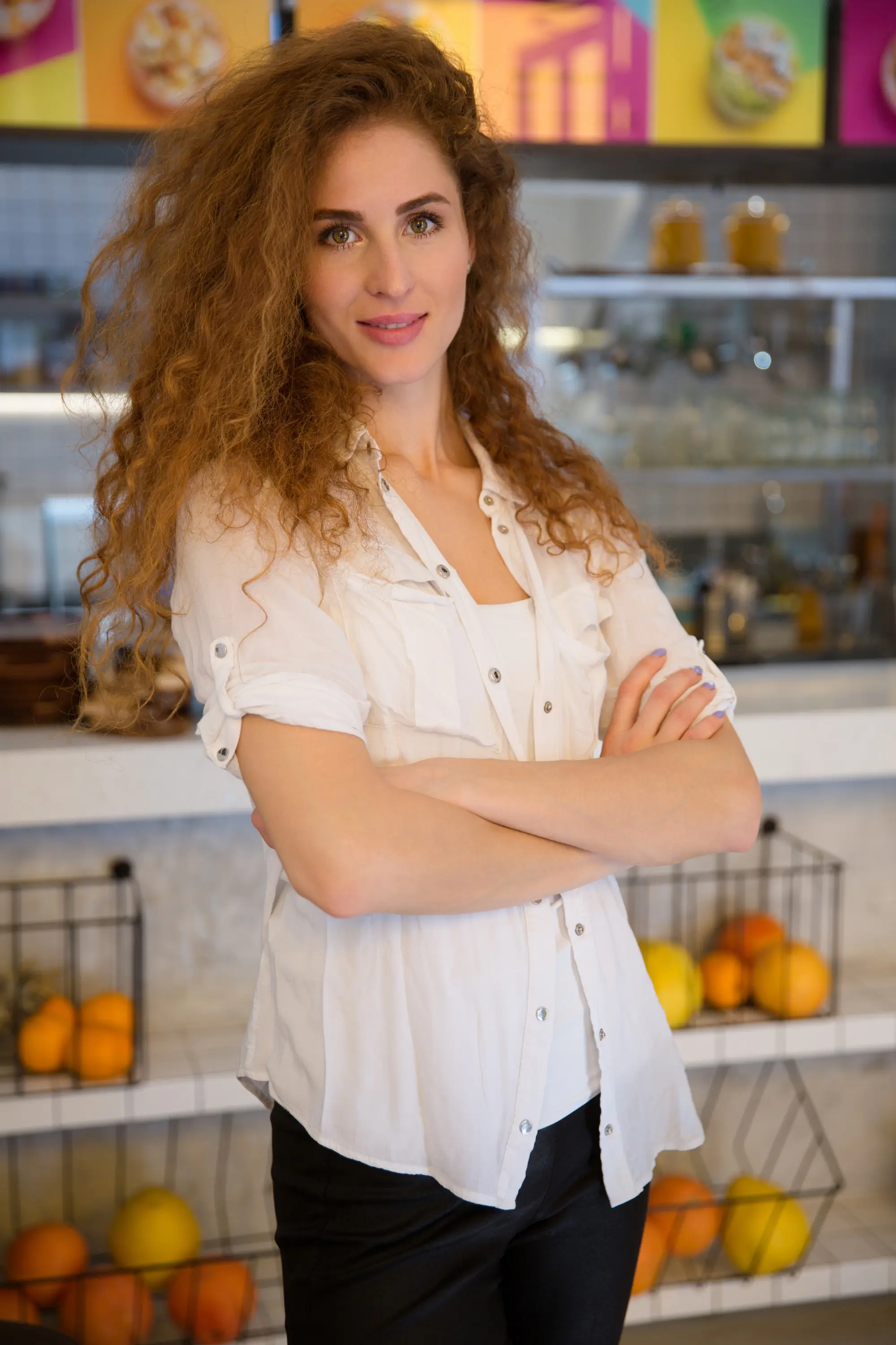Woman with curly hair and a light-colored shirt stands confidently