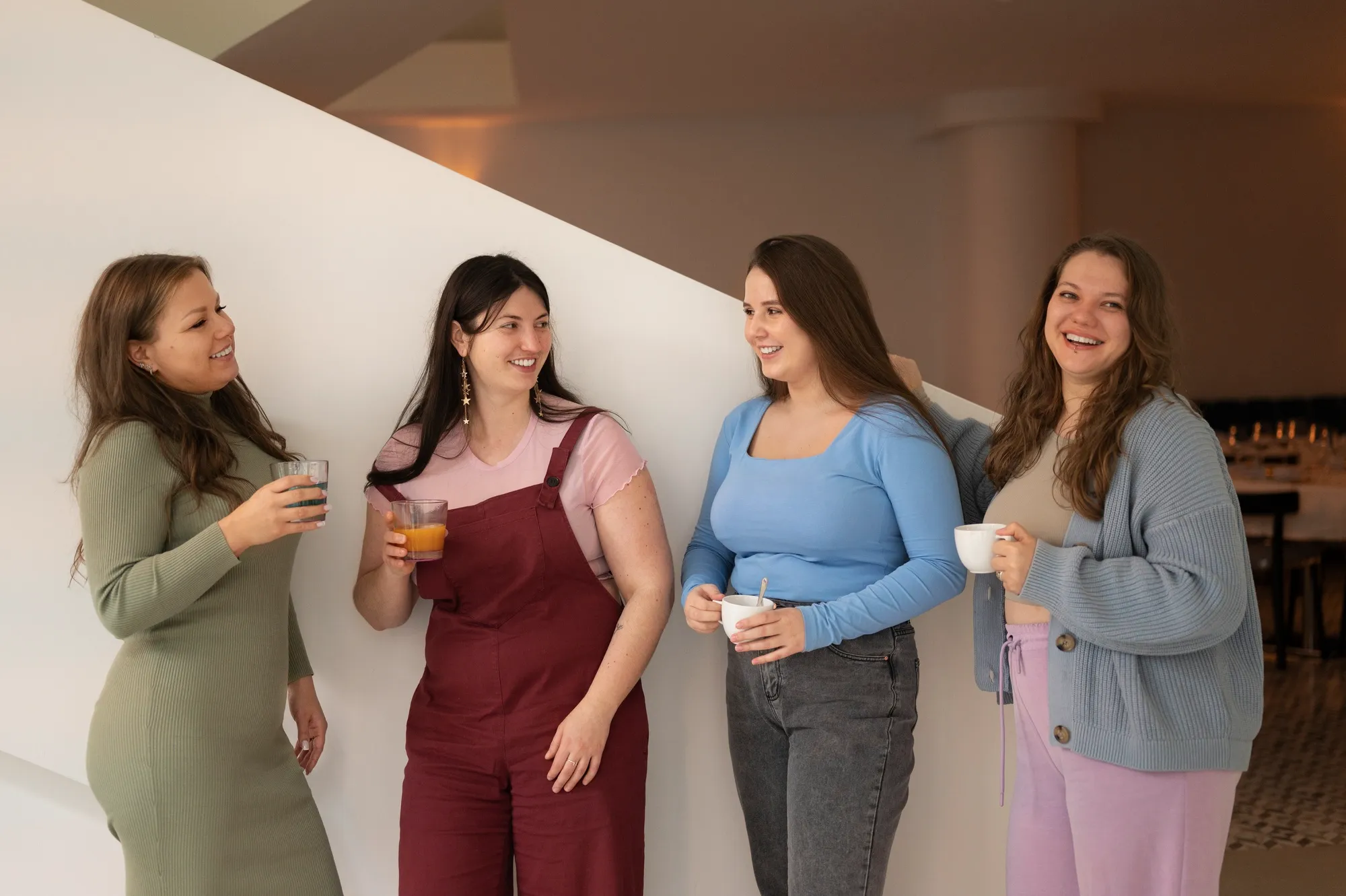 Four women stand together, smiling and chatting