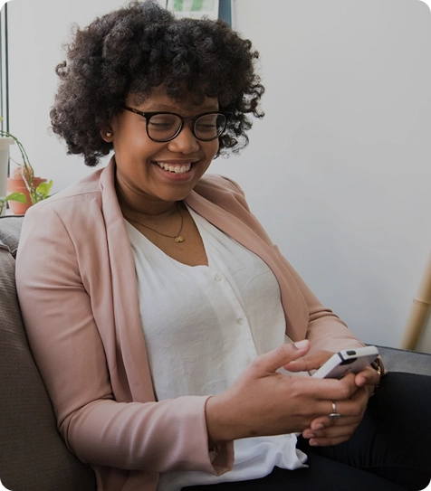Woman sitting on a couch holding a smartphone