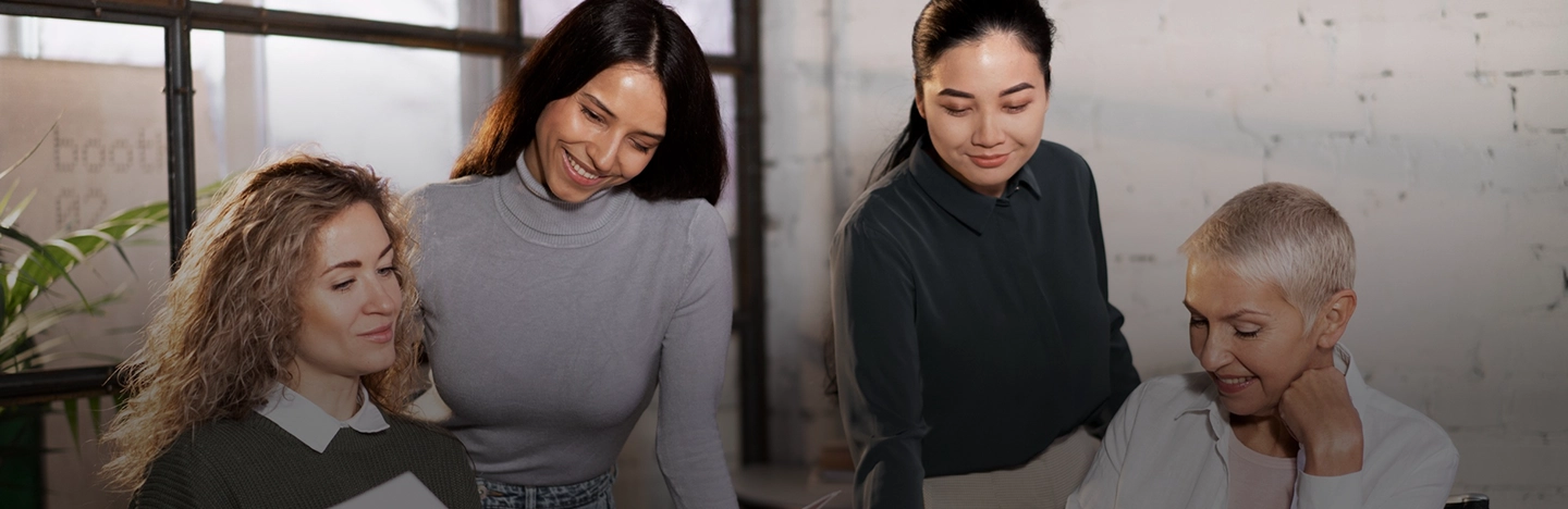 Four women gathered around a desk